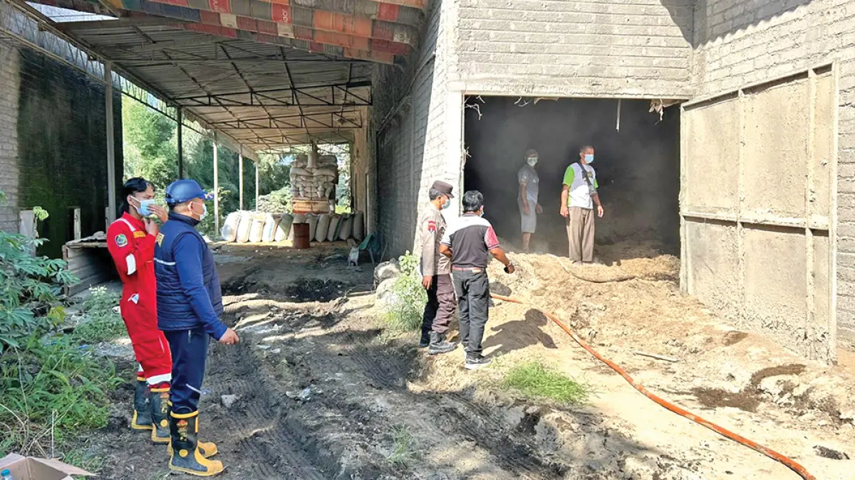 PENDINGINAN: Anggota Polsek Singojuruh bersama tim Damkarmat Banyuwangi memadamkan api yang membakar limbah sekam di pabrik penggilingan padi di Desa Benelan Kidul, Kecamatan Singojuruh, Jumat (3/4). (Foto: Polsek Singojuruh)