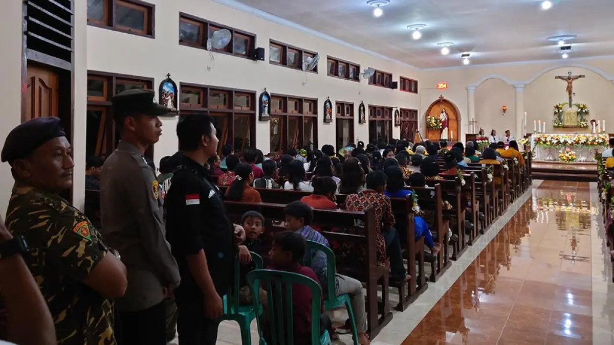 KHIDMAT: Perayaan Misa Paskah di Gereja Katolik Paroki Maria Ratu Para Rasul Dusun Sumberjati, Desa Grajagan, Kecamatan Purwoharjo dijaga langsung oleh kepolisian dan  satgas lintas agama Sabtu malam (4/4). (Agus Suhartono for Radar Banyuwangi)