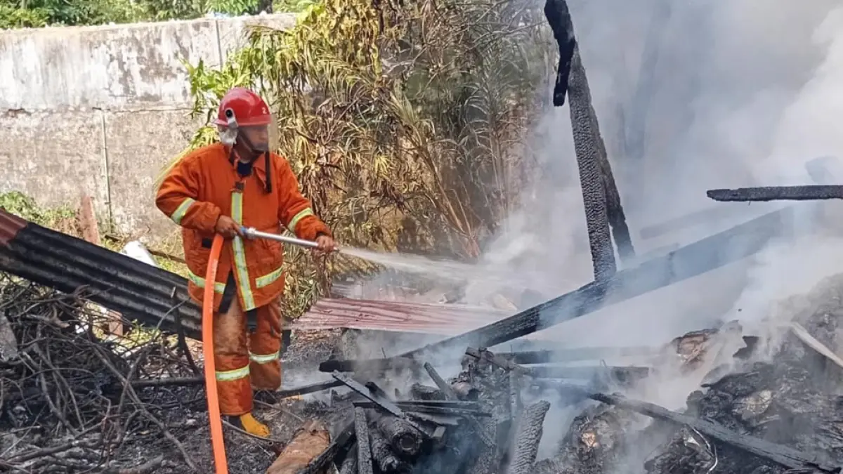 SEMPROT AIR: Petugas Damkarmat Sektor Srono memadamkan api yang membakar gudang barang bekas di Desa Wonosobo, Kecamatan Srono pada Rabu (8/4). (Heri Siswanto for Radar Banyuwangi)