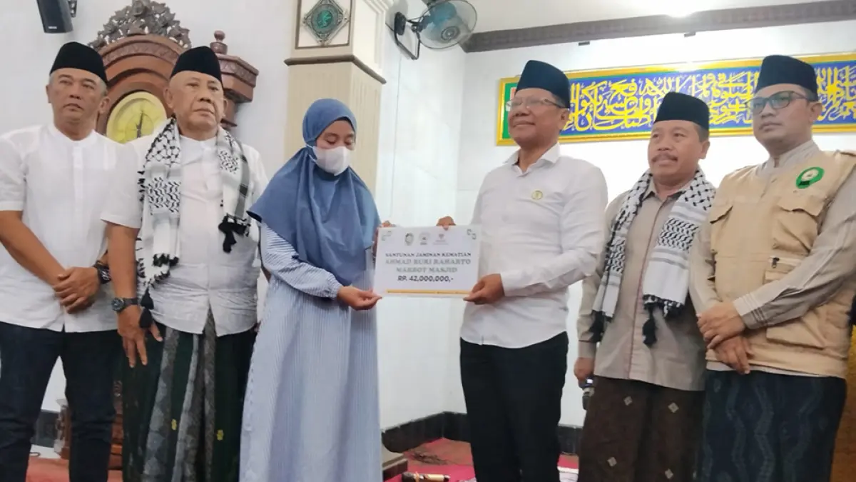 SIMBOLIS: Ketua Baznas Kabupaten Banyuwangi Dwi Yanto menyerahkan santunan kematian dari BPJS Ketenagakerjaan kepada Wiwin Setyorini, ahli waris marbot Masjid Jamik Darul Falah Desa Banjar, Kecamatan Licin, Jumat siang (10/4). (BAZNAS Banyuwangi)
