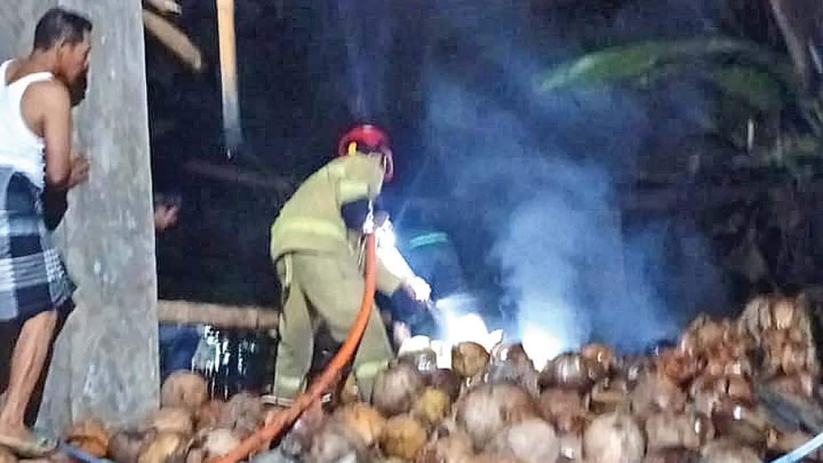 BERASAP: Petugas Damkarmat memadamkan api yang membakar tumpukan sabut kelapa di Desa Sraten, Kecamatan Cluring, Senin malam (13/4). (Heri Siswanto for Radar Banyuwangi)