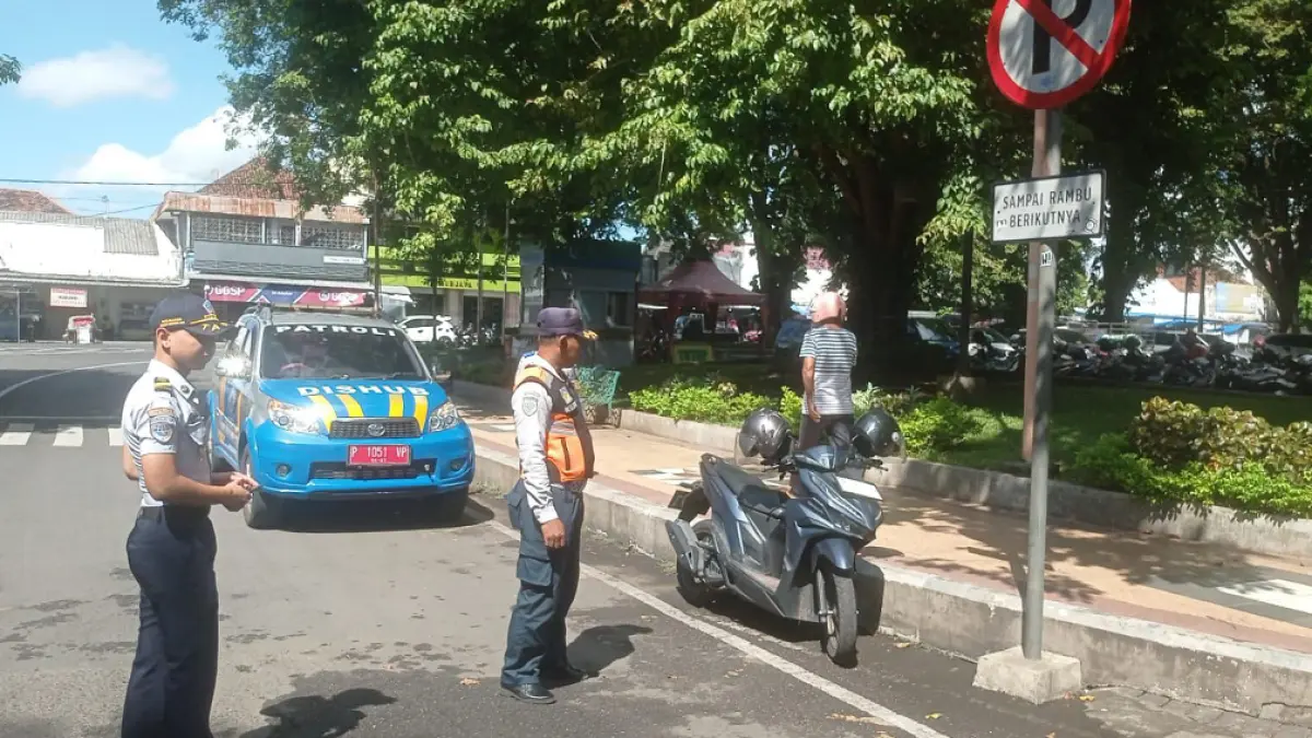 DITERTIBKAN: Petugas Dishub Banyuwangi memberikan teguran kepada sejumlah pengendara yang memarkir sepeda motornya di pinggir jalan kawasan Ttaman Sritanjung, Senin (13/4). (Bagus Rio/Radar Banyuwangi)