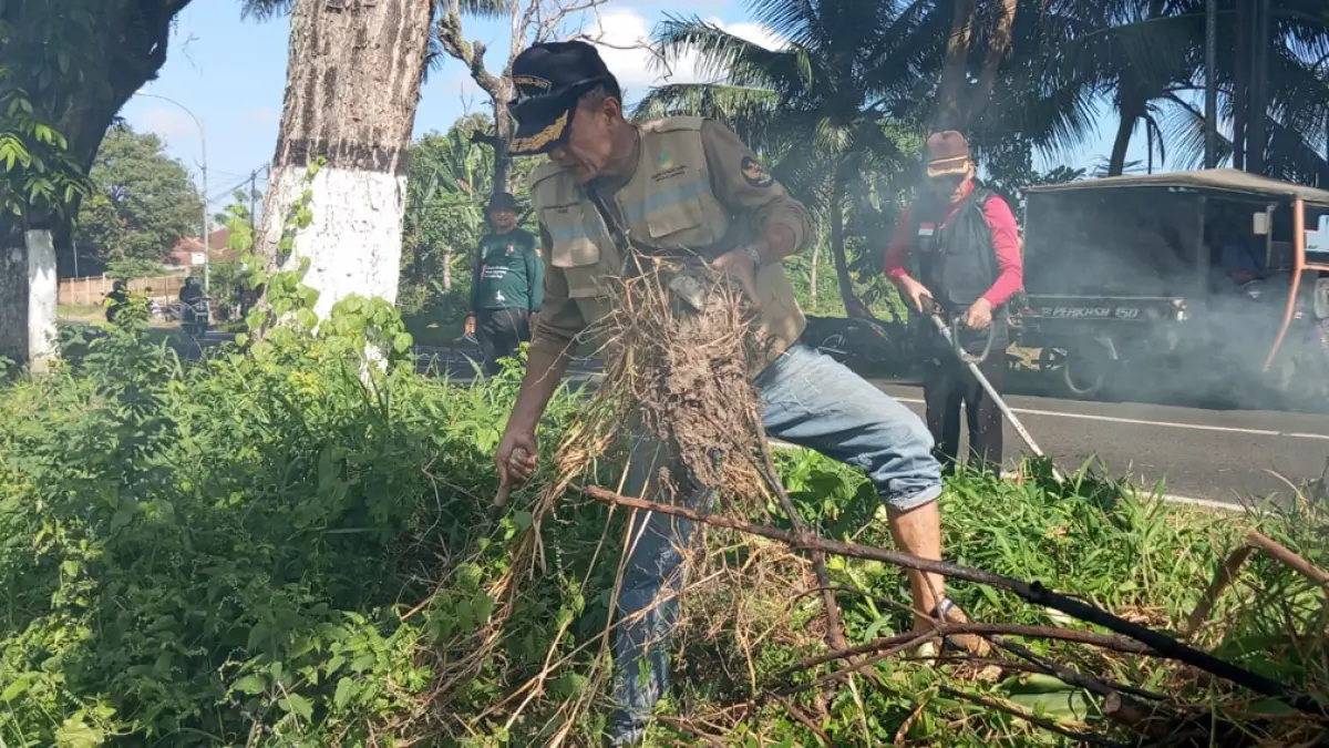 KERJA BAKTI: Perangkat desa, masyarakat, siswa, hingga petugas Kecamatan Singojuruh bersih-bersih di tepi jalan raya jurusan Singojuruh-Rogojampi, Jumat (17/4). (Iwan Yos for Radar Banyuwangi)