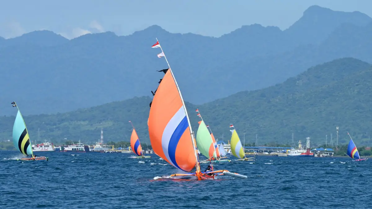 JADI TRADISI: Perahu nelayan adu asal Banyuwangi dan Bali cepat menyeberangi Selat Bali dalam Lomba Perahu Layar yang digelar para nelayan, Minggu (19/4). (Ramada Kusuma/Radar Banyuwangi)