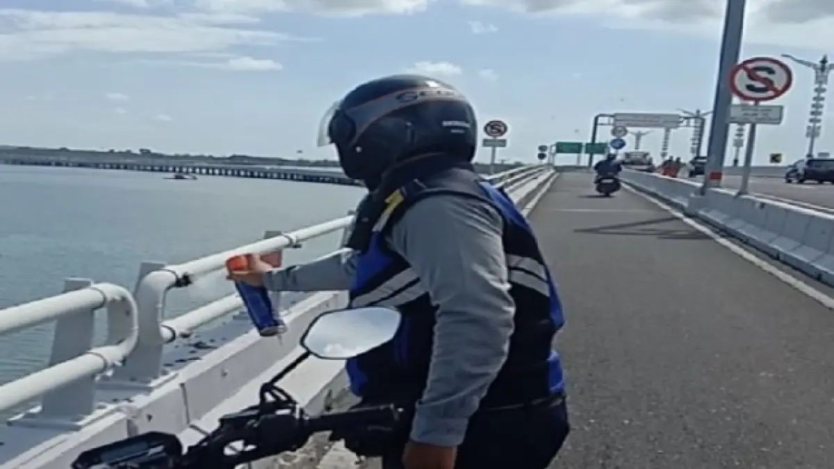 PENANGANAN: Seorang petugas mengusir gerombolan tawon di salah satu railing Jalan Tol Bali Mandara, Sabtu (18/3). (ISTIMEWA via Bali Express)