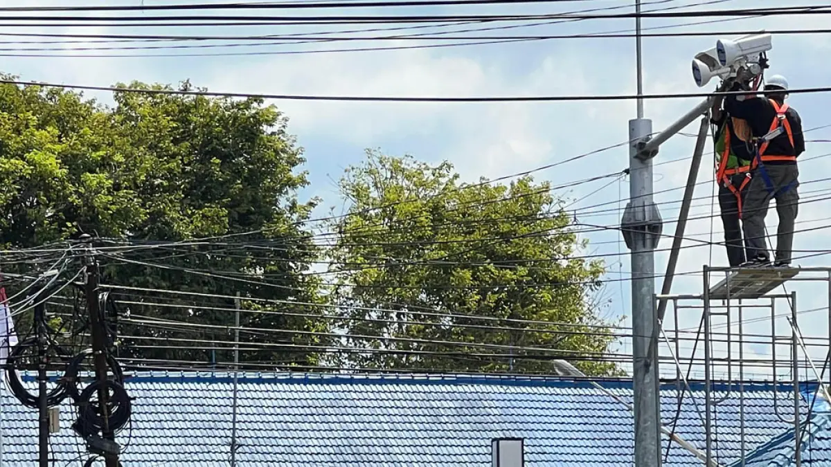 PERBAIKAN: Petugas memperbaiki kamera ETLE di simpang tiga kantor DPRD Banyuwangi, Senin (20/4). (Bagus Rio/Radar Banyuwangi)