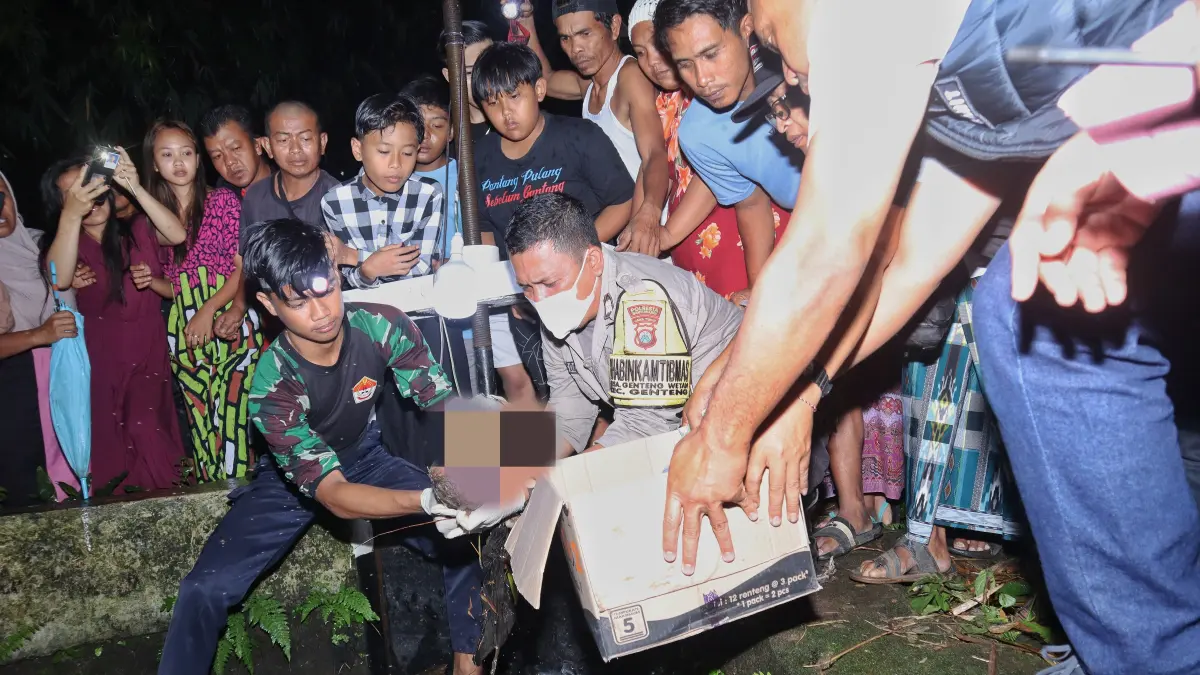 TKP: Anggota Polsek Genteng mengevakuasi jasad bayi berkelamin laki-laki, di Dusun Krajan 1, Desa Kembiritan, Kecamatan Genteng, Selasa (21/4). (SALIS ALI/JP-RABA)