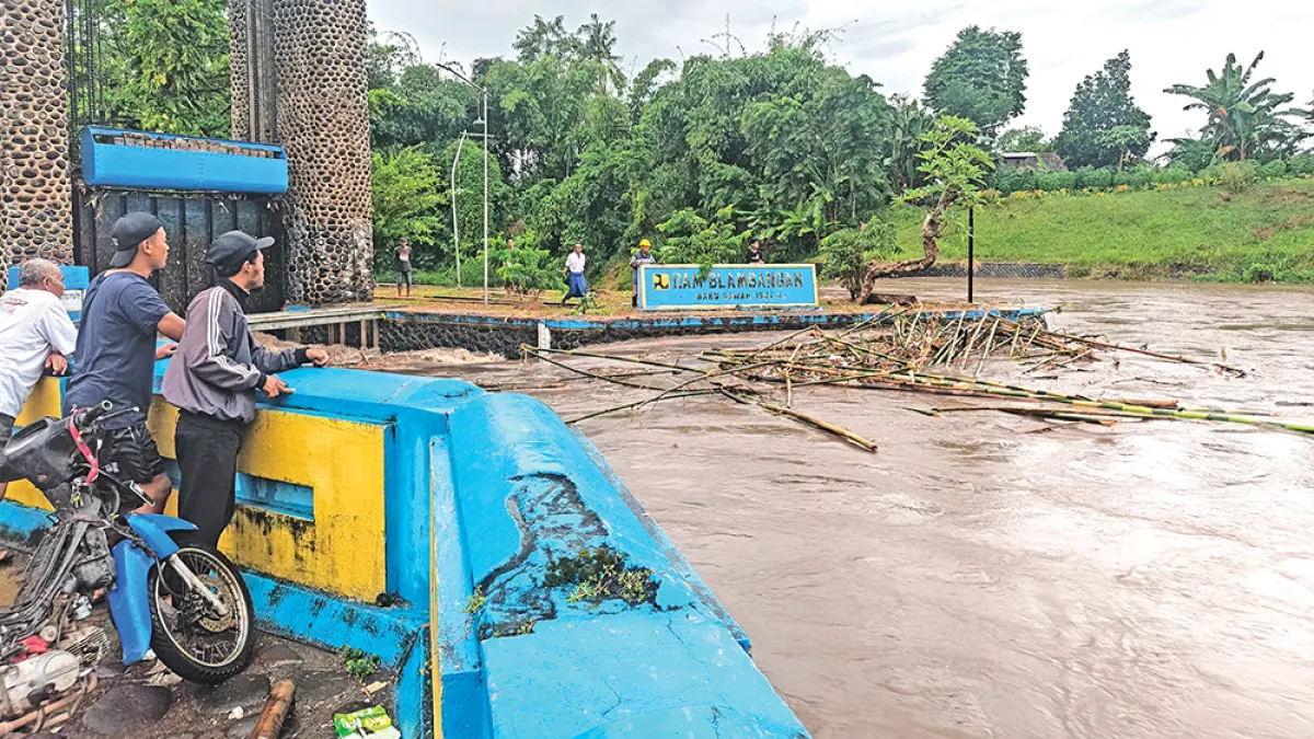 HANYUT: Petugas pintu air memantau aliran air yang membawa sampah dan kayu di Dam Singir, Selasa (21/4). (Zamrozi Wahyu/Radar Banyuwangi)