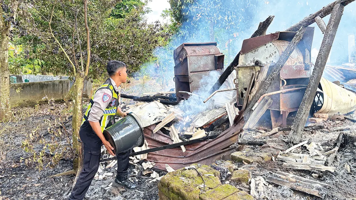 PERALATAN SEADANYA: Petugas Polsek Kalibaru memadamkan api yang melahap gudang alat pertanian di Dusun Terongan, Desa Kebonrejo, Kecamatan Kalibaru, Selasa sore (20/4). (Eko Ari for Radar Banyuwangi)