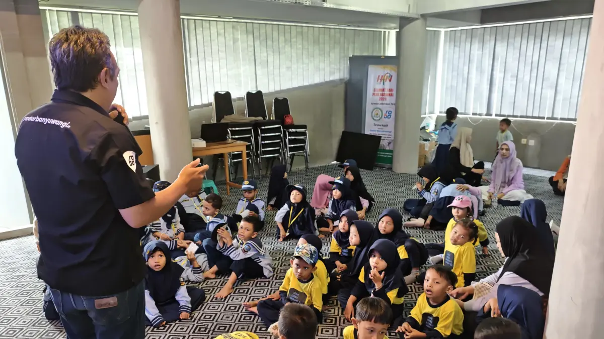 Siswa TK Khadijah 137 (seragam kuning) dan TK Darul Amien (seragam biru) mendengarkan penjelasan dari Staf Redaksi Jawa Pos Radar Banyuwangi, Niklaas Andries, di Ruang Seblang, Rabu (22/4/2026). (Lugas Rumpakaadi/Radar Banyuwangi)