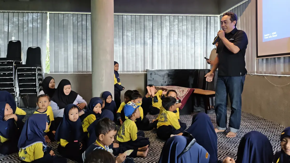 Staf redaksi Jawa Pos Radar Banyuwangi, Niklaas Andries mengajak siswa TK Khadijah 137 dan TK Darul Amien berkeliling kantor Grha Pena, Rabu (22/4/2026). (Lugas Rumpakaadi/Radar Banyuwangi)