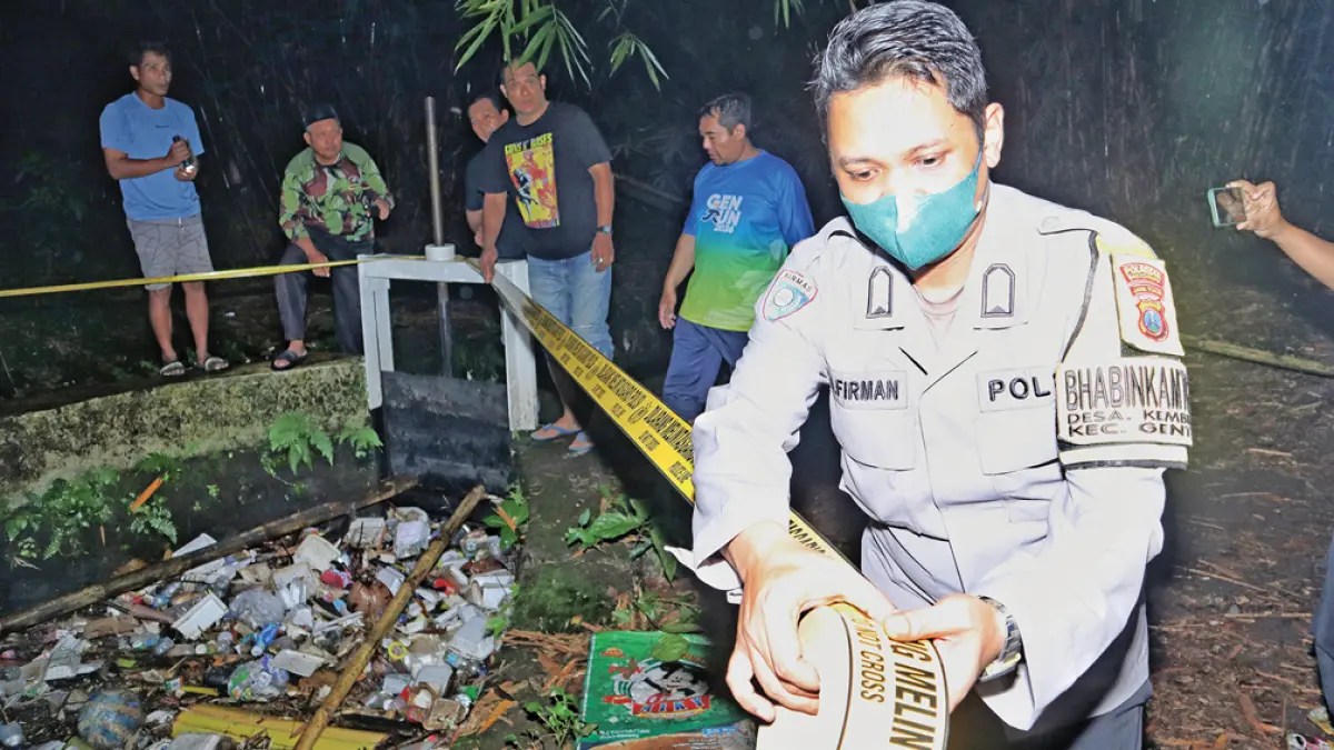 TKP: Anggota Polsek Genteng memasang garis polisi di sekitar TKP pembuangan bayi di Dusun Krajan 1, Desa Kembiritan, Kecamatan Genteng. (Salis Ali/Radar Banyuwangi)