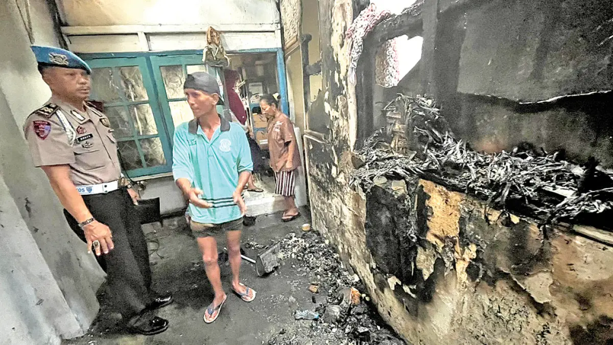 HANGUS: Anggota Polsek Singojuruh memeriksa rumah warga yang terbakar akibat korsleting listrik di Dusun Juruh, Desa/Kecamatan Singojuruh, Kamis (23/4). (Achmad Rudy for Radar Banyuwangi)