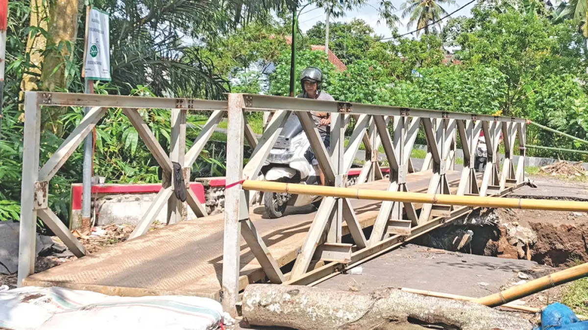 KHUSUS RODA DUA: Pengendara sepeda motor melintas di jembatan darurat Dusun Tapansari, Desa Sraten, Kecamatan Cluring, Kamis (23/4). (Zamrozi Wahyu/Radar Banyuwangi)
