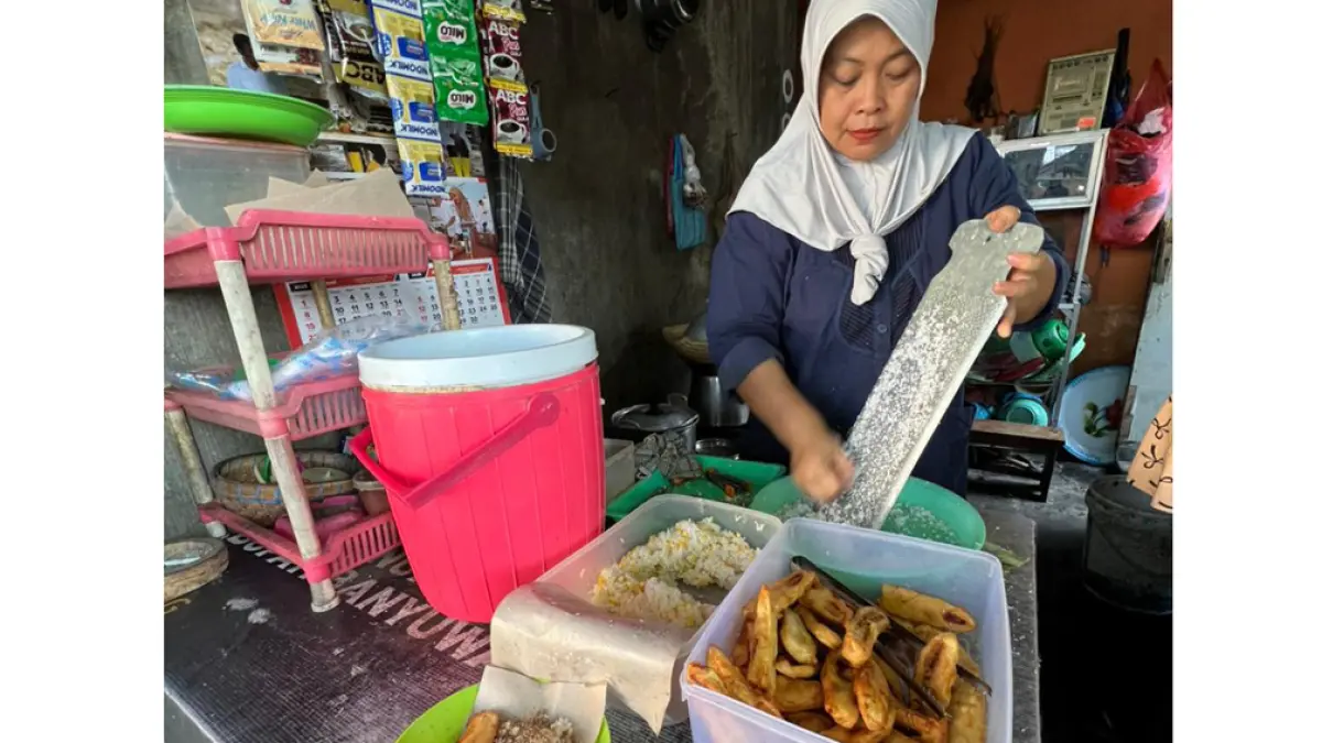 MASIH HANGAT: Mutimah memarut kelapa untuk toping menu ketan kirip dan ketan jagung di teras rumahnya Penataban, Giri, Jumat (24/4). (Bagus Rio/Radar Banyuwangi)