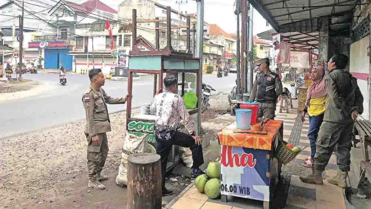 MEMBAHAYAKAN: Petugas gabungan menertibkan PKL yang berjualan di dekat lampu lalu lintas Desa Jajag, Kecamatan Gambiran, Kamis (23/4). (Suyanto for Radar Banyuwangi)
