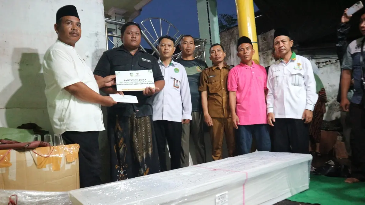 Wakil Ketua Bidang Distribusi Baznas Kabupaten Banyuwangi, Nanang Khoirurozik (paling kiri), menyerahkan uang duka kepada anak almarhumah M. Ramadhani di rumah duka, disaksikan pengurus UPZ Kecamatan Muncar dan perwakilan dari Kantor Kecamatan Muncar, pada Senin malam (27/4/2026). (Baznas Kabupaten Banyuwangi)
