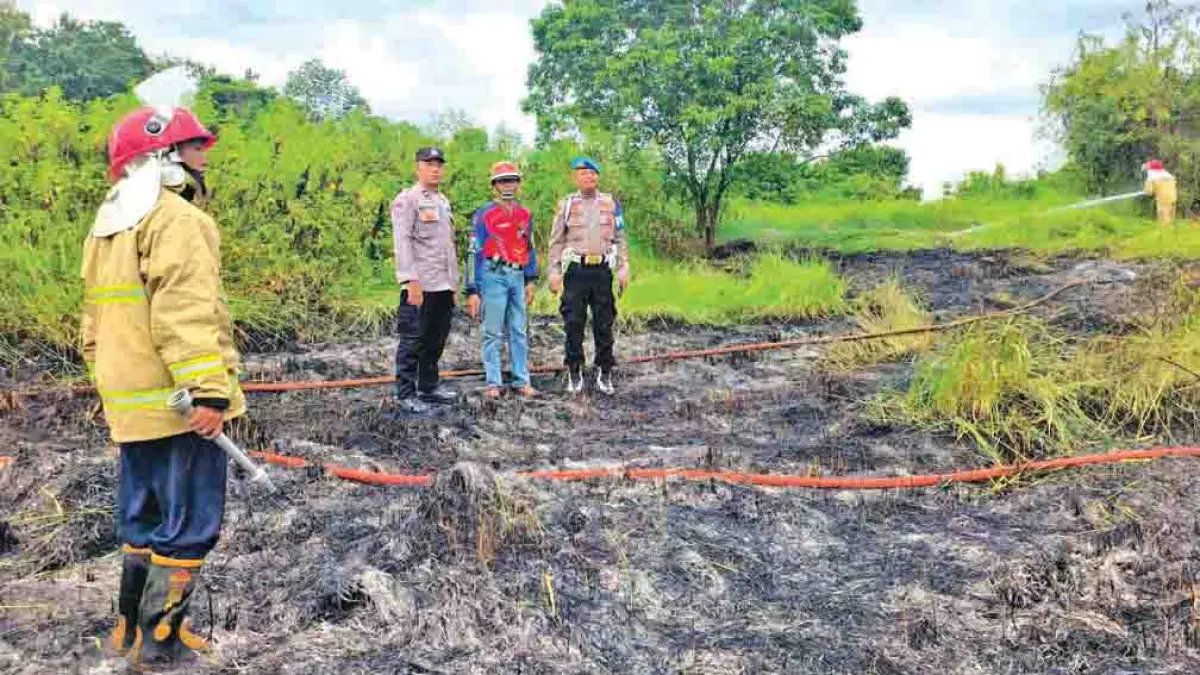 HANGUS: Petugas Damkarmat memadamkan api di lahan kosong di Desa Benelan Kidul, Kecamatan Singojuruh, Minggu (26/4). (Damkarmat Banyuwangi)