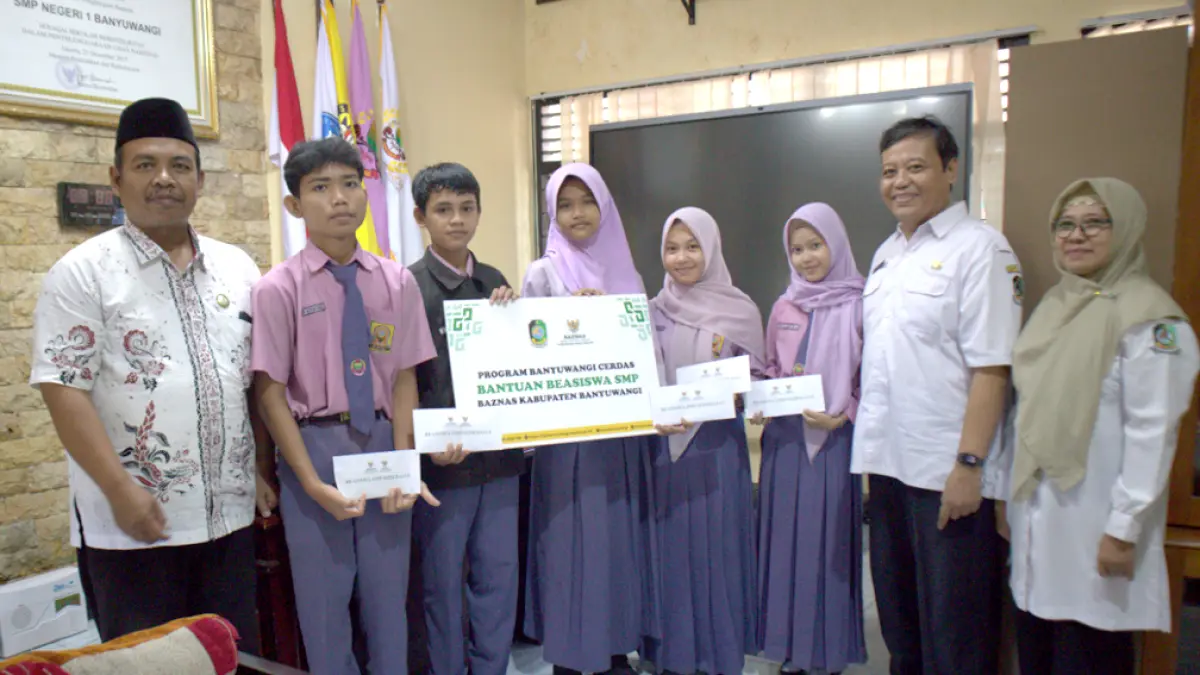 GEMBIRA: Wakil Ketua Bidang Distribusi Baznas Banyuwangi Nanang Khoirurozik (paling kiri) foto bersama lima siswa penerima beasiswa dan dua guru pembina SMPN 1 Banyuwangi Rabu pagi (29/4). (Dok. Baznas Banyuwangi)