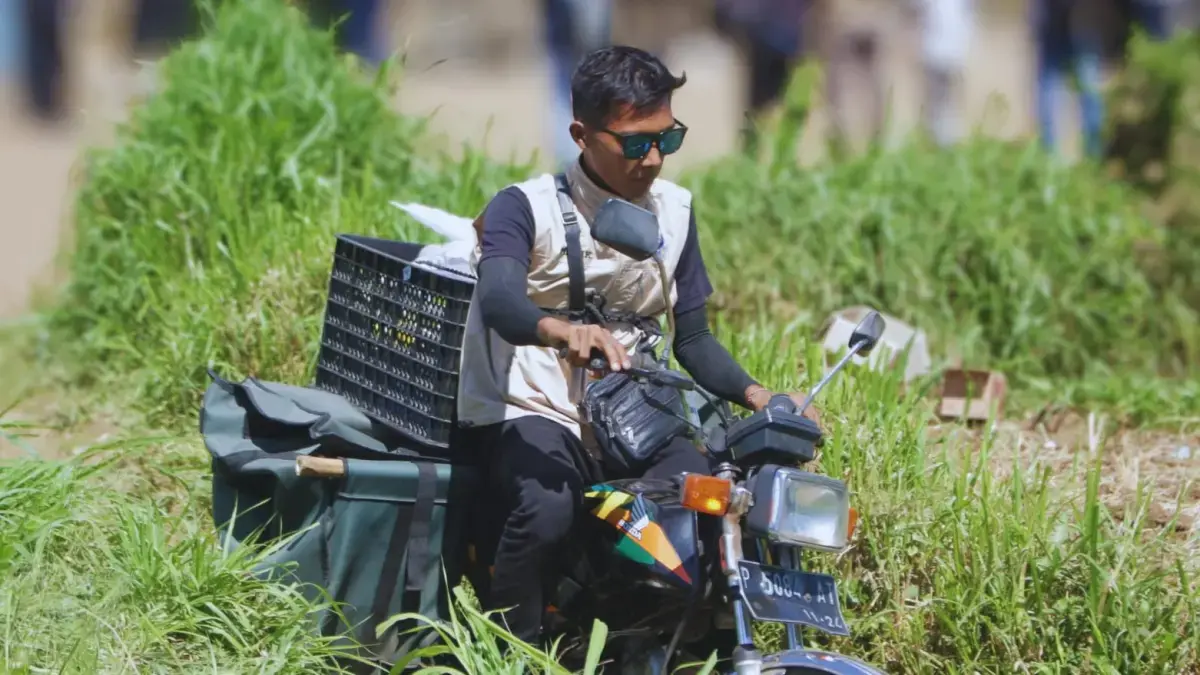 PENUH TANTANGAN: Abdul Malik, petugas distribusi MBG dari SPPG Wringin II mengantarkan makanan kepada siswa di SDN Banyuwulu 4 Bondowoso. (ILHAM WAHYUDI/RADAR IJEN)
