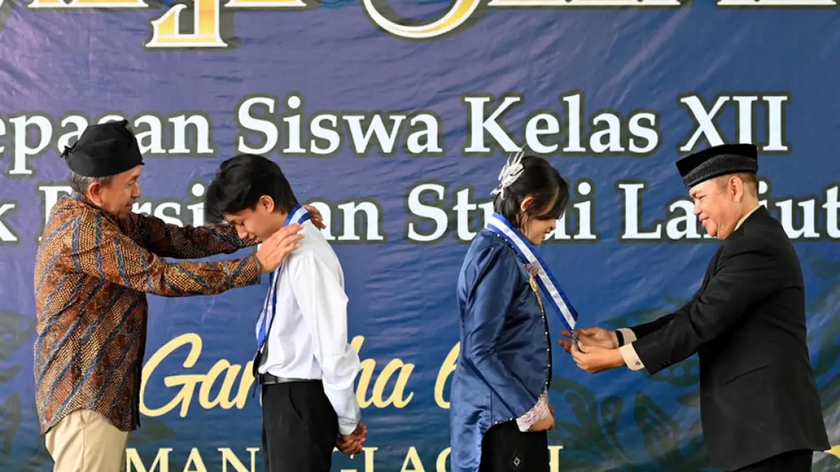 LULUS: Kepala SMAN 1 Glagah Abdullah bersama Anggota Komite SMAN 1 Glagah Yudi mengalungkan gordon sebagai simbol kelulusan siswa kelas XII pada rangkaian prosesi Purna Widya Satria Tama di SMAN 1 Glagah, Rabu (6/5). (Ramada Kusuma/Radar Banyuwangi)