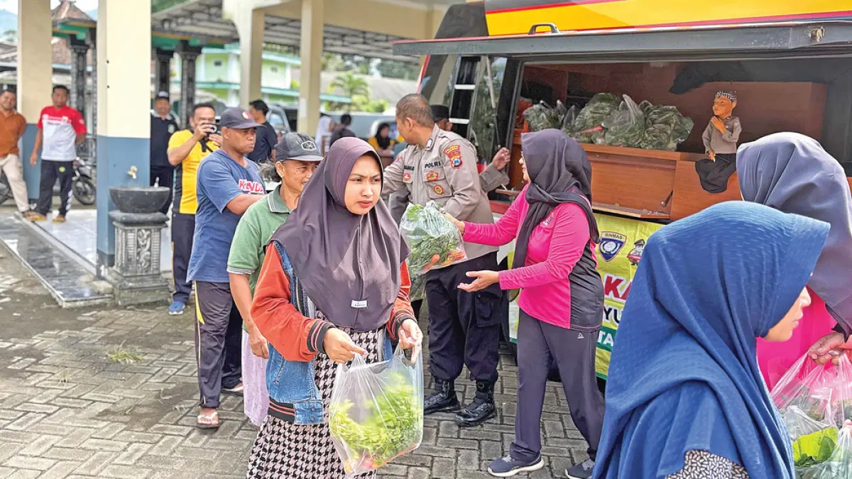 Warga menerima sayur dan lauk pauk saat kegiatan Mayur Kamtibmas (Mobil Sayur Kamtibmas) di Desa Kalibarumanis, Kecamatan Kalibaru, Jumat (8/5). (Salis Ali/Radar Banyuwangi)