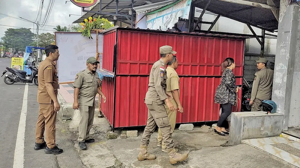 PENERTIBAN: Petugas Satpol PP BKO V Genteng menertibkan sejumlah stan PKL di trotoar kawasan RTH Maron, Desa Gentengkulon, Kecamatan Genteng, Senin (11/5). (Salis Ali/Radar Banyuwangi)