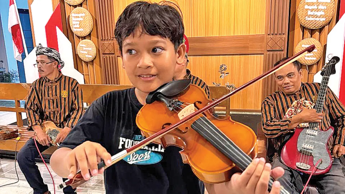 ANGGOTA TERMUDA: Bagas, siswa kelas 4 SDN 4 Penganjuran, turut melestarikan musik keroncong bersama para personel Keroncong Genta Sritanjung. (Ksatria Raya/Radar Banyuwangi)