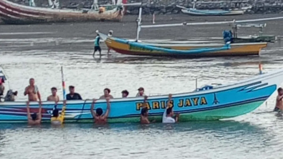 KECELAKAAN: Para nelayan membantu evakuasi perahu yang dihantam ombak di perairan Pelawangan, Pantai Grajagan, Desa Grajagan, Kecamatan Purwoharjo, Senin sore (18/5). (Andik for Radar Banyuwangi)