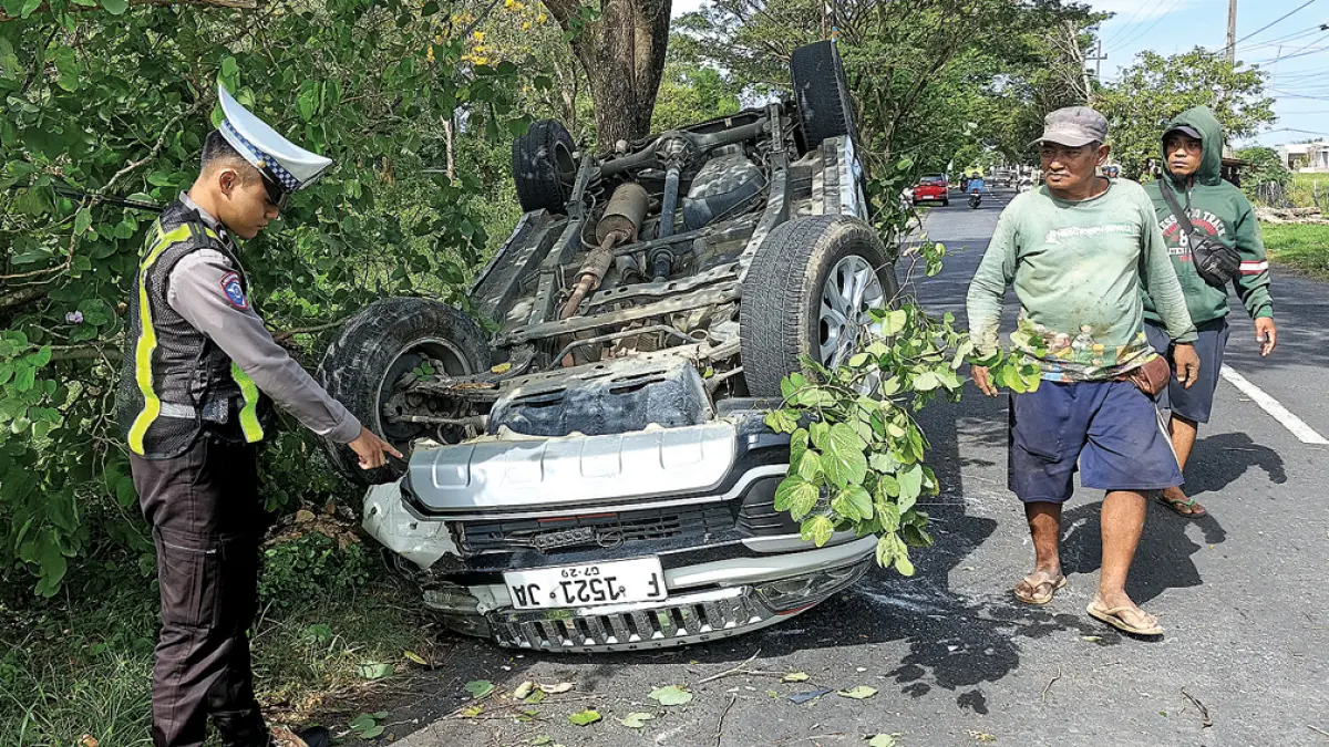 OLAH TKP: Anggota lantas Polsek Rogojampi menunjukkan mobil yang mengalami kecelakaan tunggal di Jalan Raya Rogojampi-Blimbingsari di Desa/Kecamatan Rogojampi, Senin (18/5). (Gatot for Radar Banyuwangi)