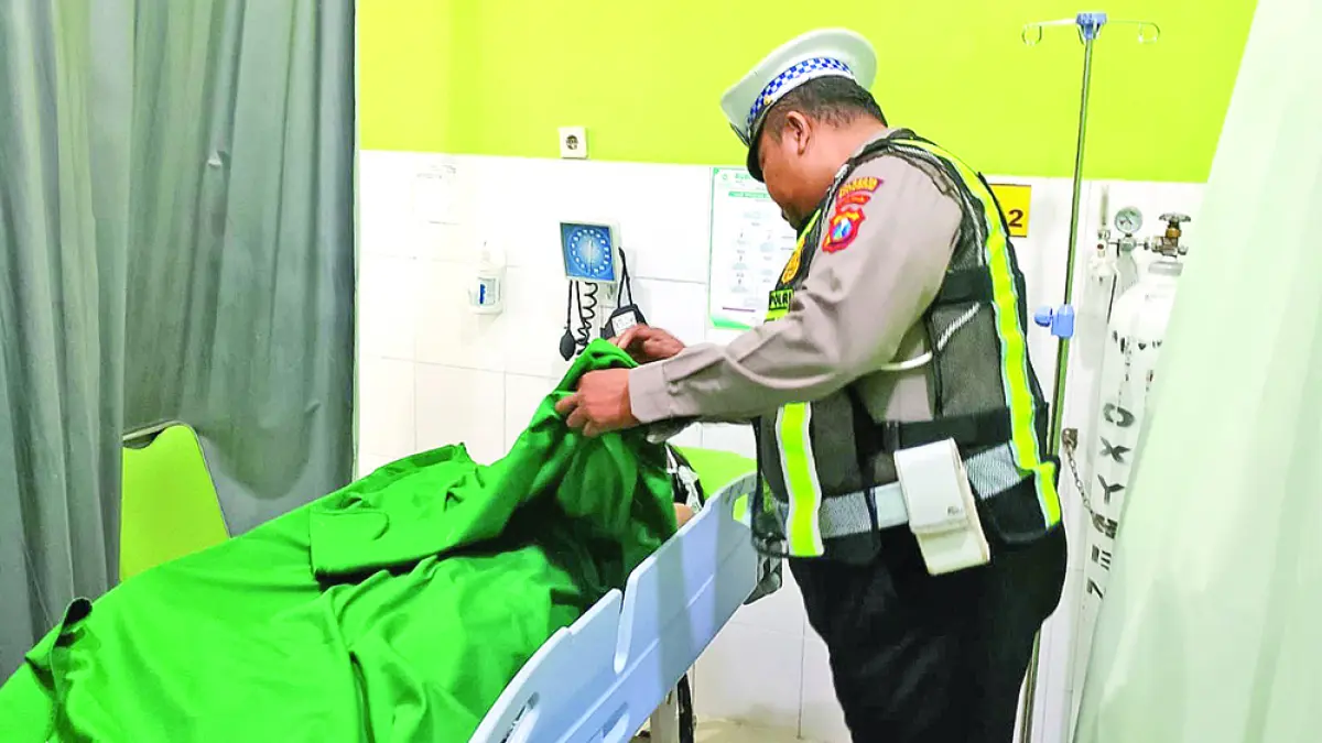 TRAGIS: Anggota Unit Lantas Polsek Genteng saat mengecek kondisi AGC, 22, yang meninggal dunia usia mengalami luka akibat benturan dengan besi hollow kotak Rabu (20/5). (Salis Ali/Radar Banyuwangi)