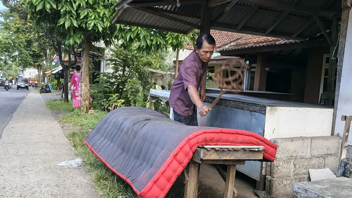 TURUN-TEMURUN : Sugiono, salah satu Suku Oseng sedang menjemur kasur di depan rumahnya yang berada di Desa Kemiren, Kamis (21/5). (Ksatria Raya/Radar Banyuwangi)