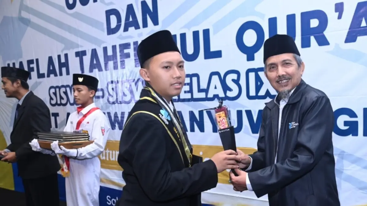 Pembina Yayasan Al Uswah Anshori SPd SSt menyerahkan apresiasi kepada siswa SMPIT Al Uswah dalam Uji publik dan Haflah Tahfizhul Quran, Sabtu (23/5/2026) di Hall Aston Banyuwangi. (Ramada Kusuma/Radar Banyuwangi)