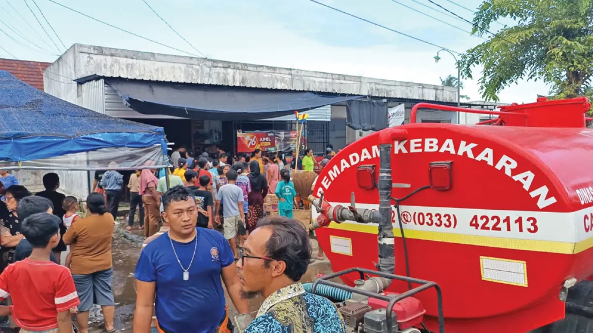 DIBANTU WARGA: Mobil damkarmat dikerahkan untuk memadamkan api di salah satu toko kelontong Pasar Desa Tapanrejo, Kecamatan Muncar, Kamis (21/5). (Slamet Hariyadi for Radar Banyuwangi)