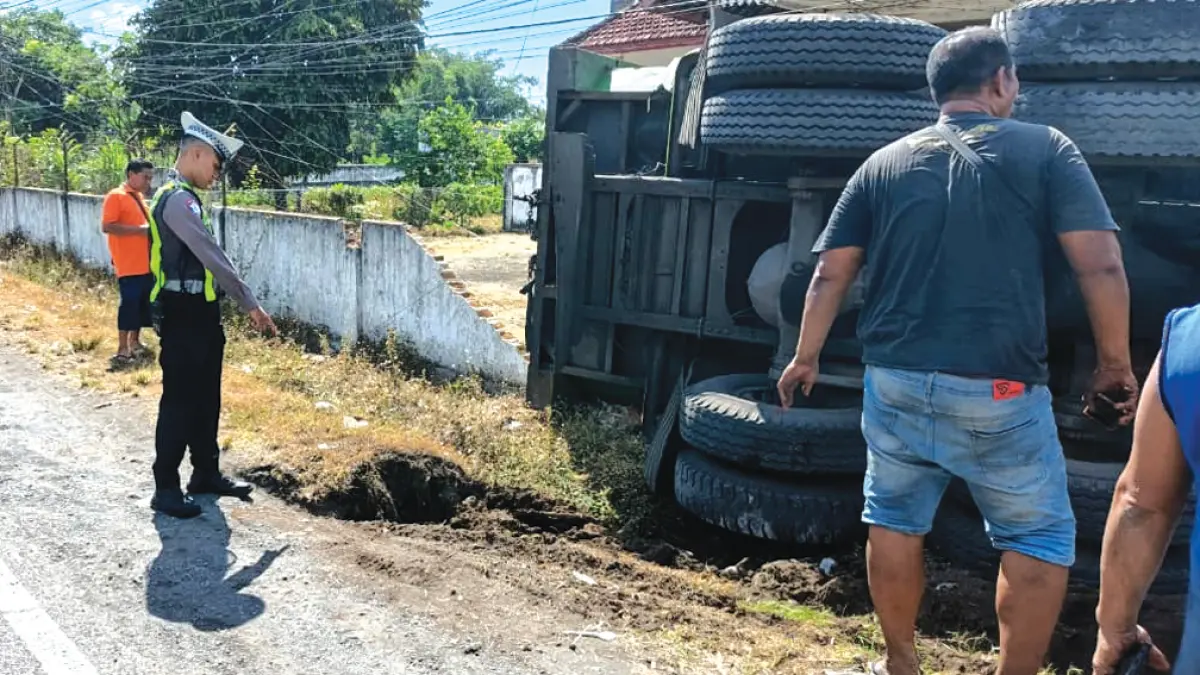 KECELAKAAN TUNGGAL: Anggota lantas Polsek Rogojampi melakukan olah TKP truk tronton yang terguling di Jalan Raya Dusun Krajan, Desa Gladag, Kecamatan Rogojampi, Minggu (24/5). (Gatot for Radar Banyuwangi)