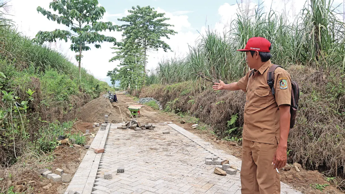 UNTUK WARGA: Kepala Dusun Darungan, Desa Tegalharjo, Kecamatan Glenmore menunjukkan lokasi proyek pavingisasi jalan utama menuju wilayahnya. (Salis Ali/Radar Banyuwangi)
