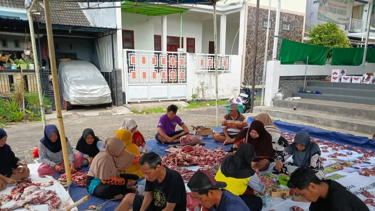 BERBAUR : Bapak-bapak dan Ibu-ibu warga Perumahan Villa Bukit Mas Blok Barat terlihat memotongi daging kurban dari 14 ekor kambing yang nantinya dibagikan ke warga sekitar (Gerda/RadarBanyuwangi.id)