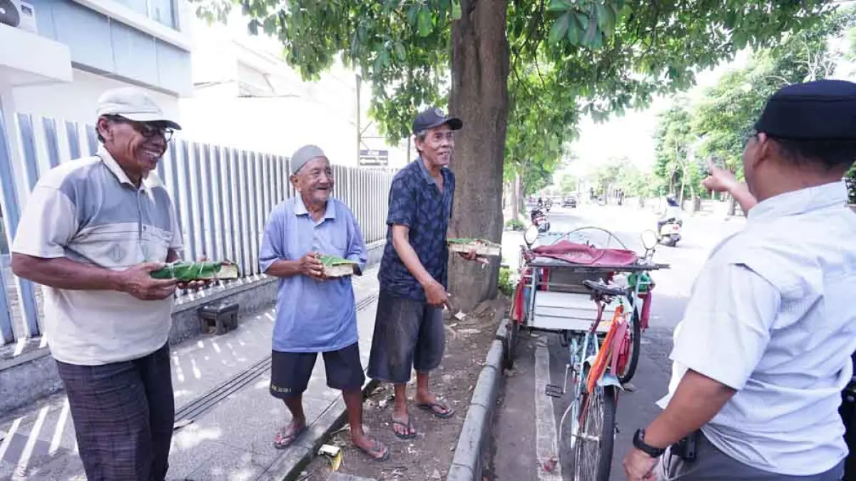 SEMRINGAH: Asisten Pembangunan Pemkab Banyuwangi M Yanuarto Bramuda menyerahkan daging kurban kepada tukang becak yang mangkal di Jalan A Yani pada Rabu (27/5). (Dini for Radar Banyuwangi)