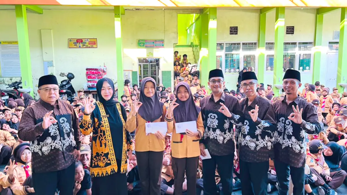MEMBANGGAKAN: Dua siswi MI Islamiyah yang meraih nilai baik-istimewa TKA mendapatkan apresiasi dari para guru di halaman MI Islamiyah Rogojampi Jumat (29/5). (Bagus Rio/Radar Banyuwangi)