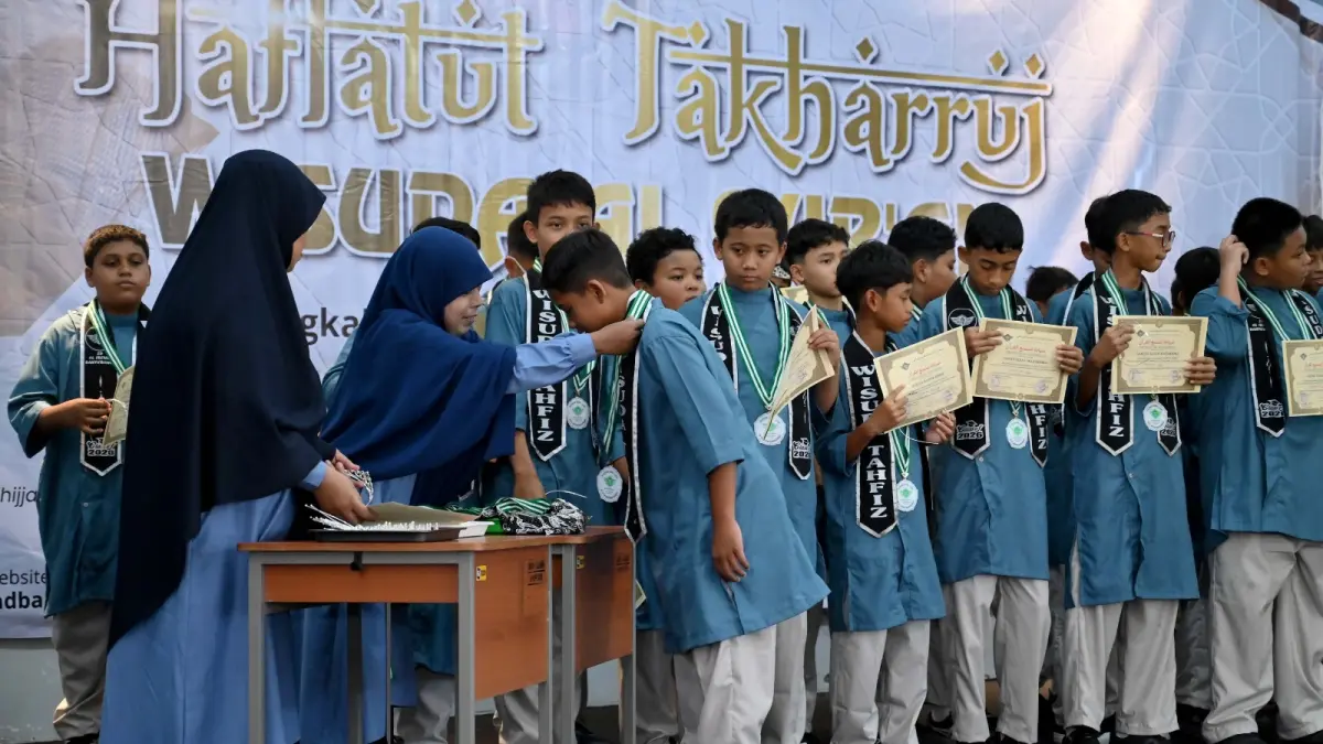 Kepala SD Al Irsyad Al Islamiyah Banyuwangi, Salwa, mengalungkan tanda kelulusan kepada salah satu siswa dalam rangkaian Haflatut Takharruj atau Wisuda Al-Qur