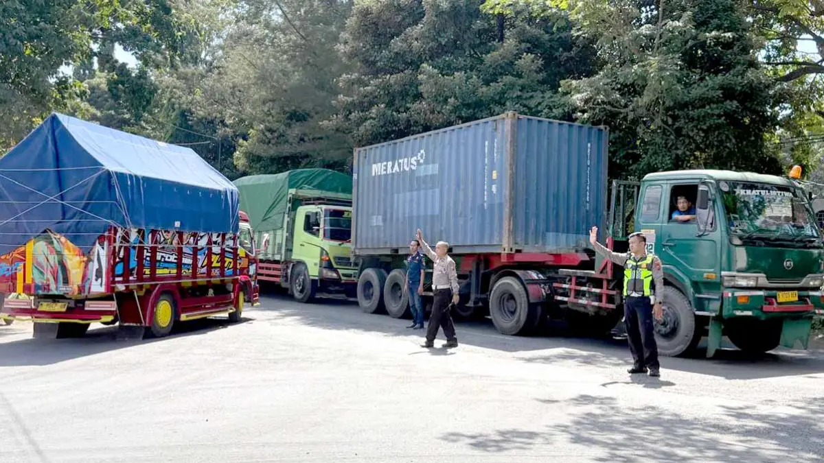 Dua personel Satlantas Polresta Banyuwangi mengatur arus lalu lintas di simpang tiga, tepatnya depan markas KPPP Tanjungwangi, Jumat (5/6). (Syaifuddin/Radar Banyuwangi)