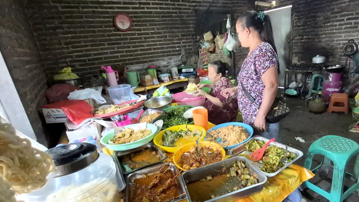 PEMBELI BERJUBEL: Bu Wagirah melayani pembeli nasi pecel di dapur rumahnya Dusun Jalen, Desa Setail, Kecamatan Genteng. (Salis Ali/Radar Banyuwangi)