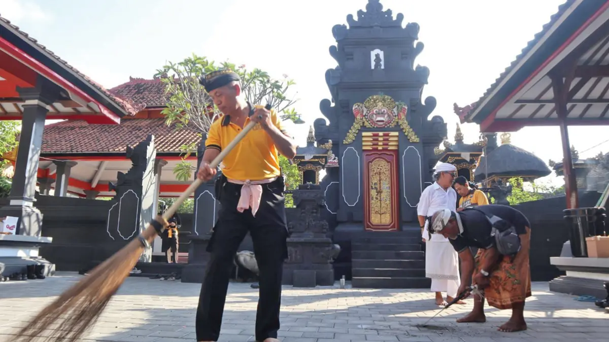 HARMONIS: Personel Polresta Banyuwangi dan Polsek jajaran gotong royong bersama warga membersihkan pura di wilayah Banyuwangi, Minggu (7/6). (Humas Polresta Banyuwangi)