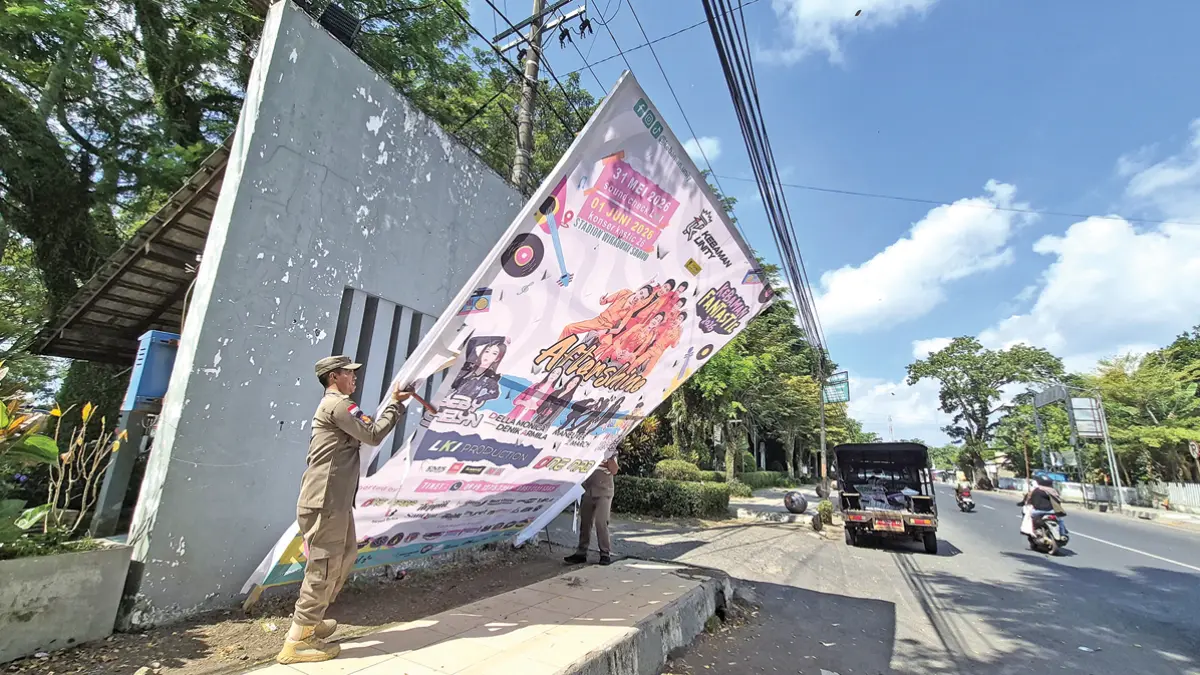 Petugas Satpol PP Kecamatan Genteng menertibkan reklame berukuran besar di sekitar RTH Maron Senin (8/6). (Salis Ali/Radar Banyuwangi)