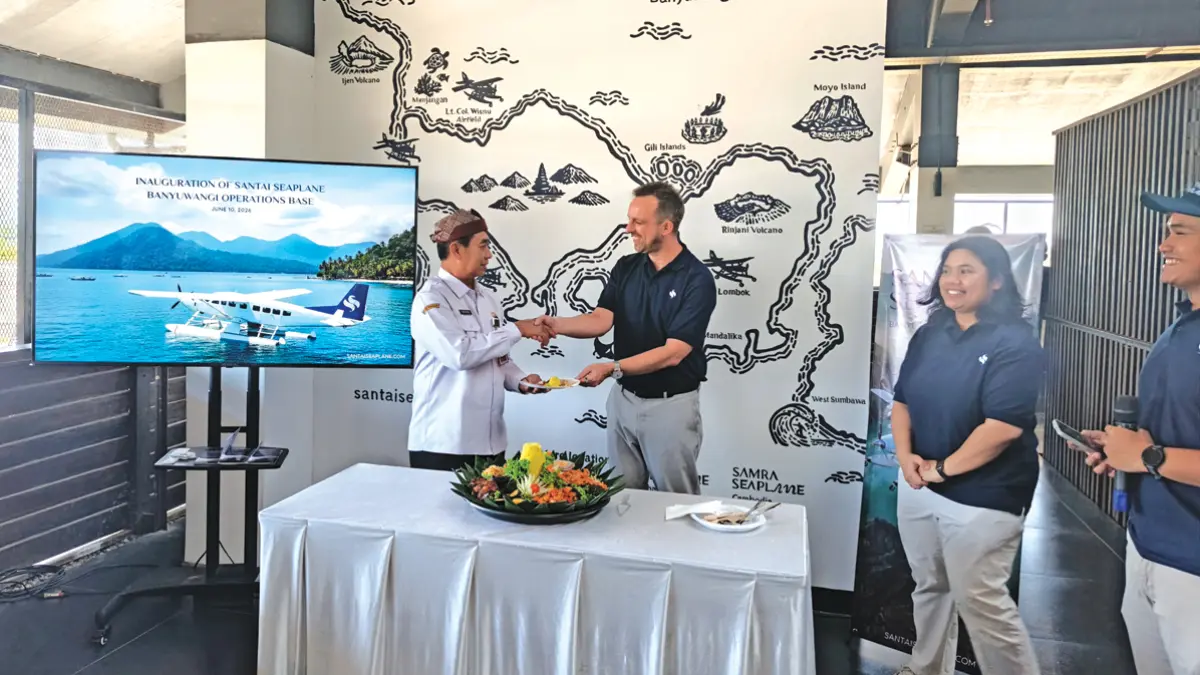 CEO Santai Seaplane Asia Dennis Keller menyerahkan potongan nasi tumpeng kepada Asisten Perekonomian dan Pembangunan Setkab Banyuwangi Suratno di Kantor Santai Seaplane di kompleks Bandara Internasional Banyuwangi, Rabu (10/6). (Zamrozi Wahyu/Radar Banyuwangi)