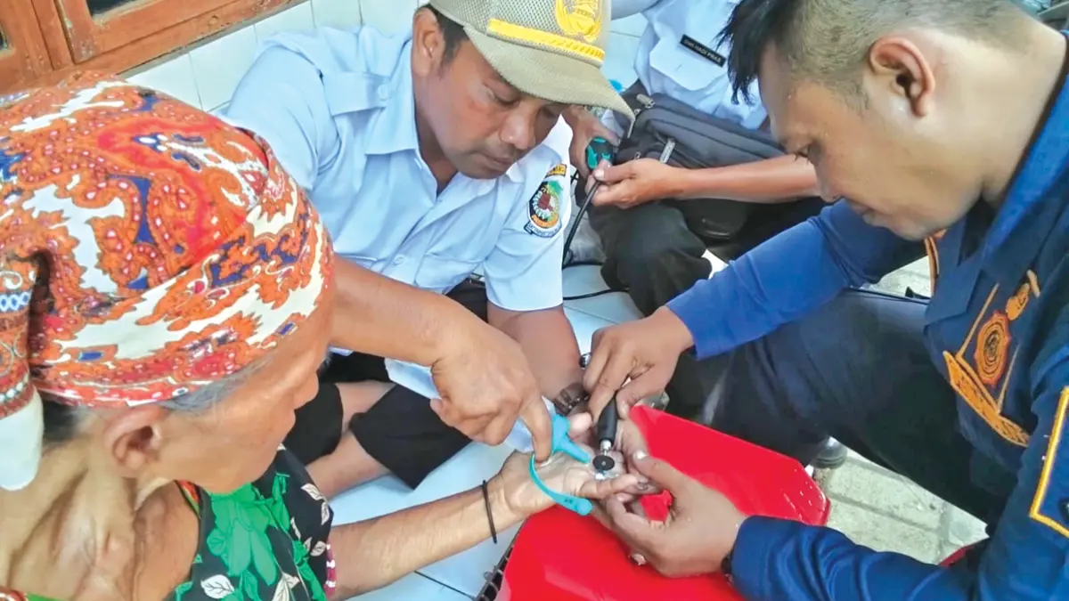 Petugas Damkramat Sektor Genteng memotong cincin logam di jari Sani, Warga Dusun Sumbergondo, Desa Tulungrejo, Kecamatan Glenmore, Rabu (10/6). (Salis Ali/Radar Banyuwangi)