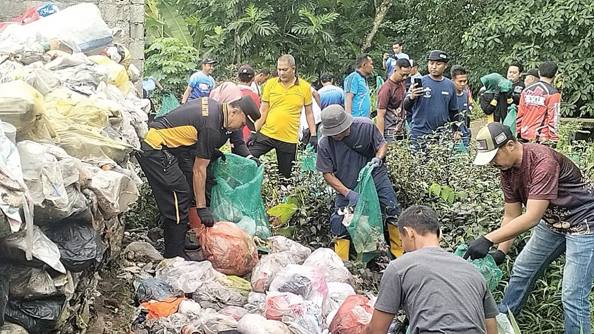 Anggota Polsek Cluring menggelar bakti sosial membersihkan sampah di tepi sungai Desa Benculuk, Kecamatan Cluring, Jumat (12/6). (Putu Ardana for Radar Banyuwangi)