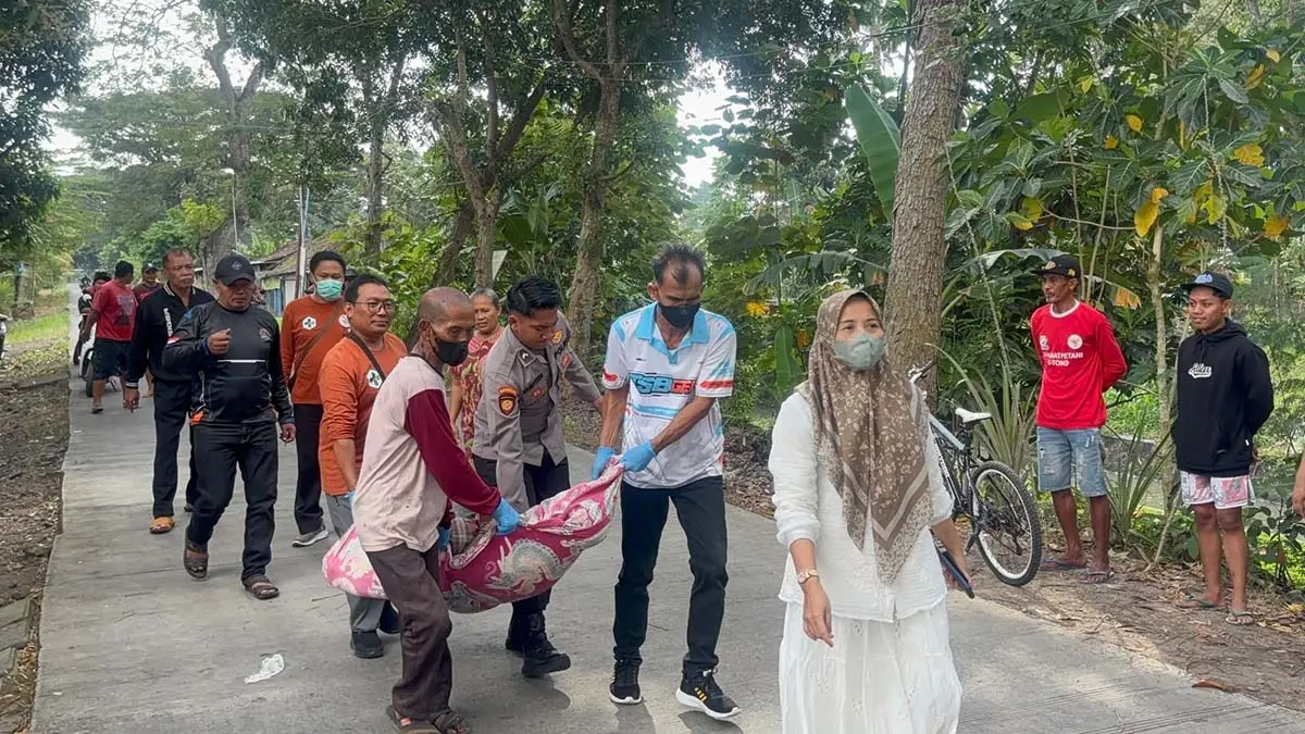Anggota Polsek Purwoharjo membantu mengevakuasi jenazah mister X yang diduga ODGJ ditemukan di tepi jalan Desa Glagahagung, Kecamatan Purwoharjo, Sabtu (13/6). (Agus Suhartono for Radar Banyuwangi)