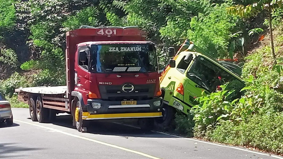BIANG MACET: Truk muatan semen terperosok di sekitar Tikungan Mbah Singo Jalan Raya Gunung Gumitir, Desa Kalibarumanis, Kecamatan Kalibaru, Minggu (14/6). (Wiji for Radar Banyuwangi)
