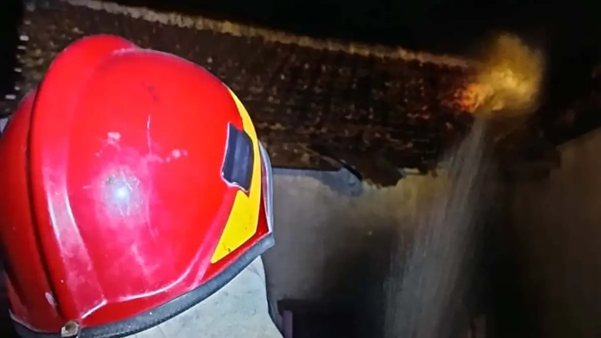 SEMPROTKAN AIR: Petugas Damkarmat Sektor Srono sedang menangani atap rumah warga Desa Tapanrejo, Kecamatan Muncar yang terbakar pada Jumat malam (12/6). (Heri Siswanto for Radar Banyuwangi)
